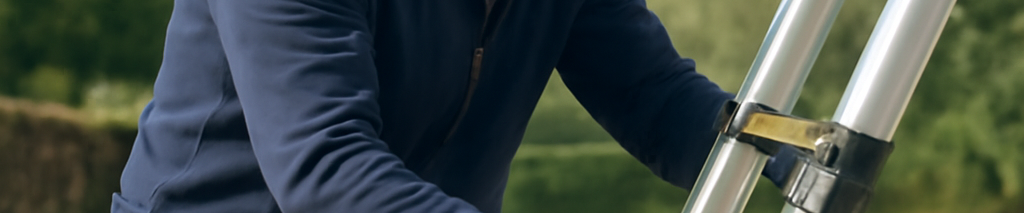 Mann stellt Teleskopleiter sicher auf stabilem Untergrund auf